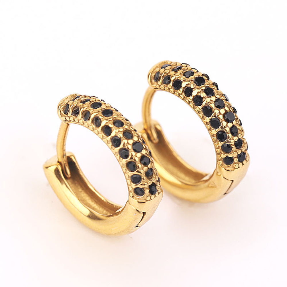Close view of gold-tone huggie earrings set with black pave stones, showing stone coverage and setting edges