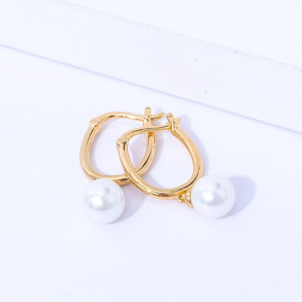 Gold-tone huggie earrings with a round freshwater pearl drop, shown as a pair