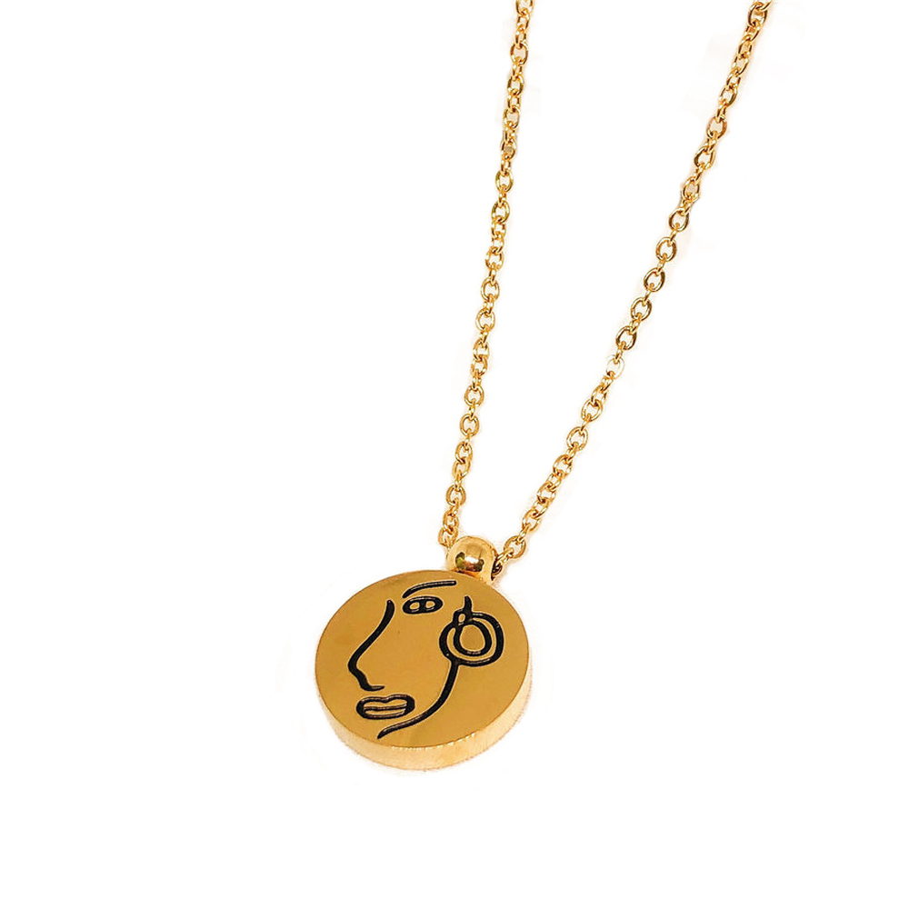 Gold-tone pendant on a fine gold chain against a pale background