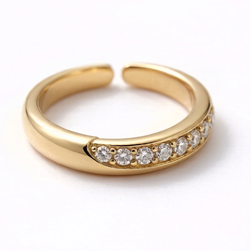 A gold-tone open band ring with a row of small cubic zirconia stones set along the band